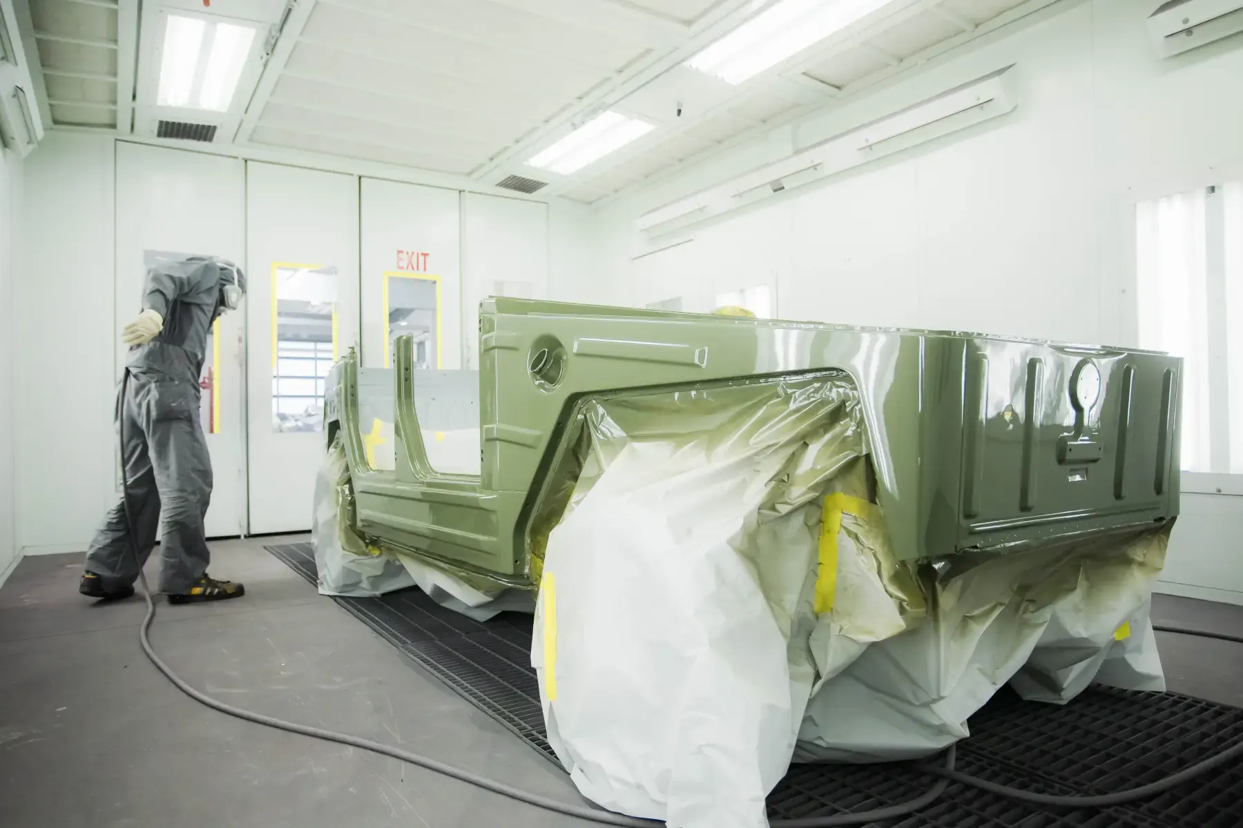 Technician refinishing a vehicle inside the climate-controlled paint booth at Kreations Auto Body
